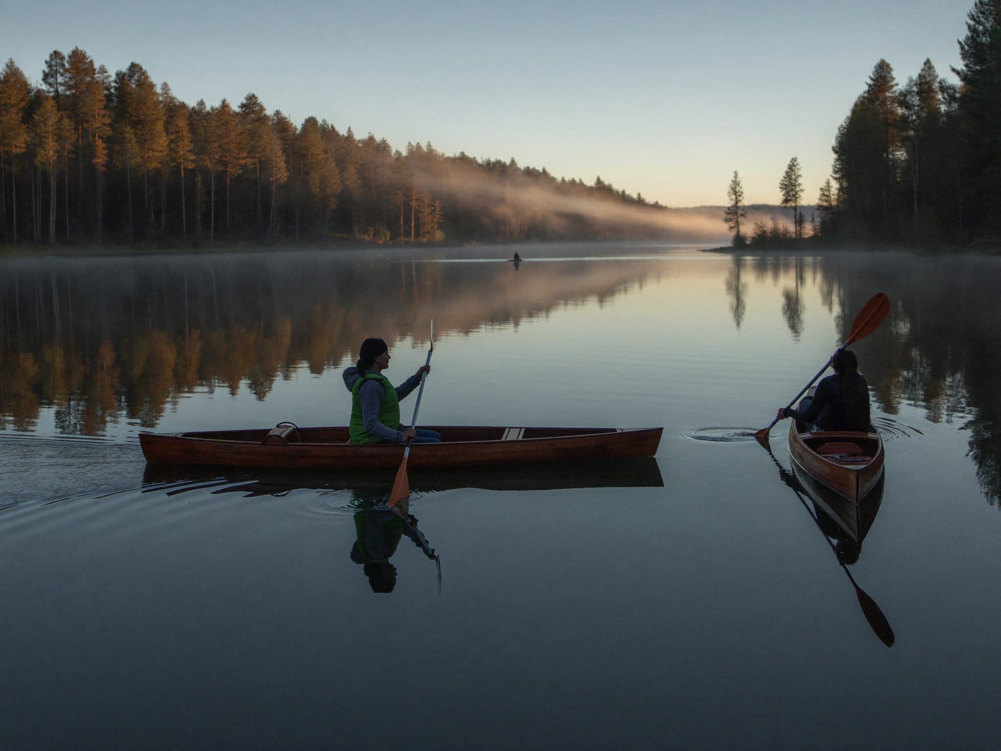 Kajaker i morgondimma på sjön